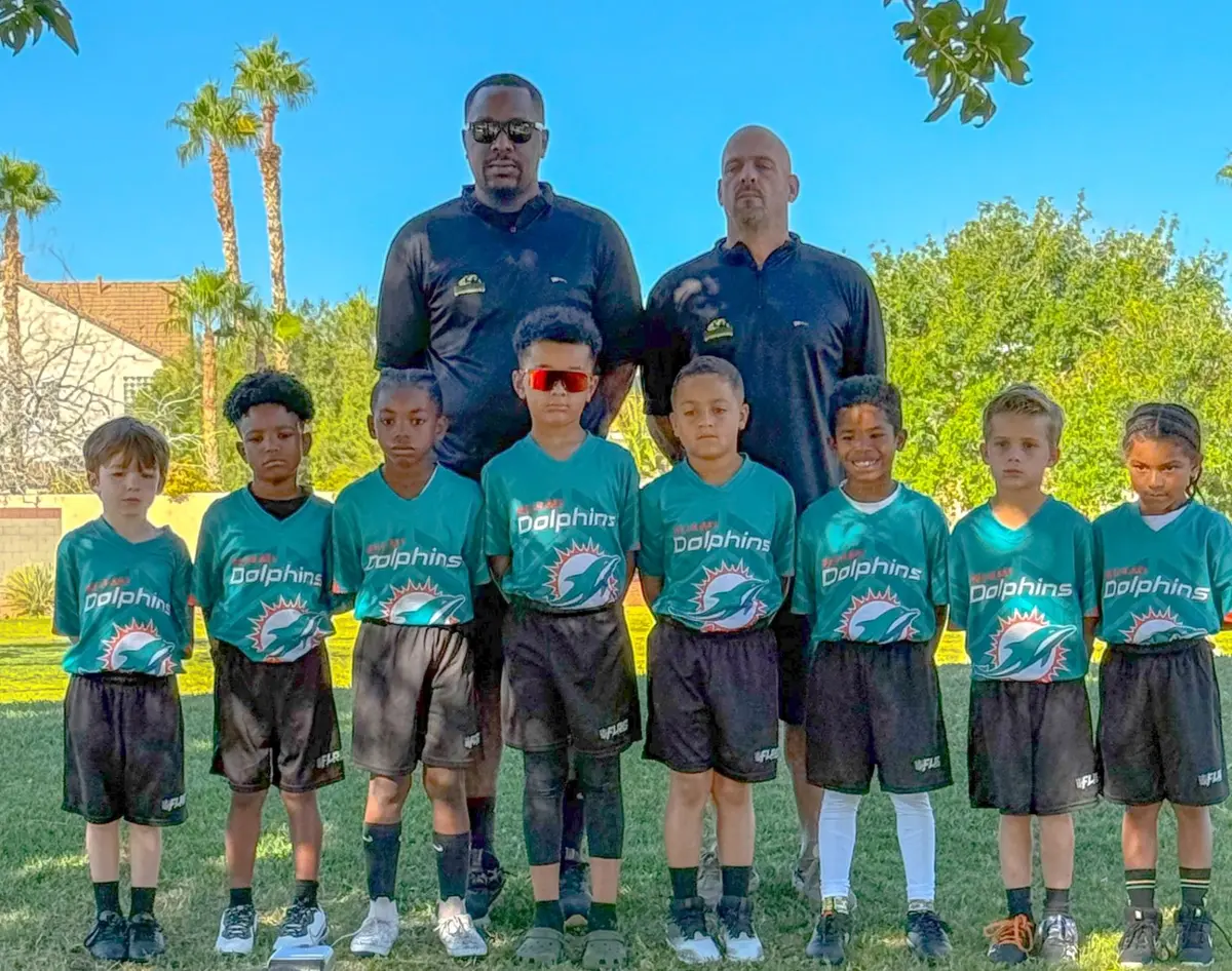 Youth football team in teal Dolphins jerseys with two coaches