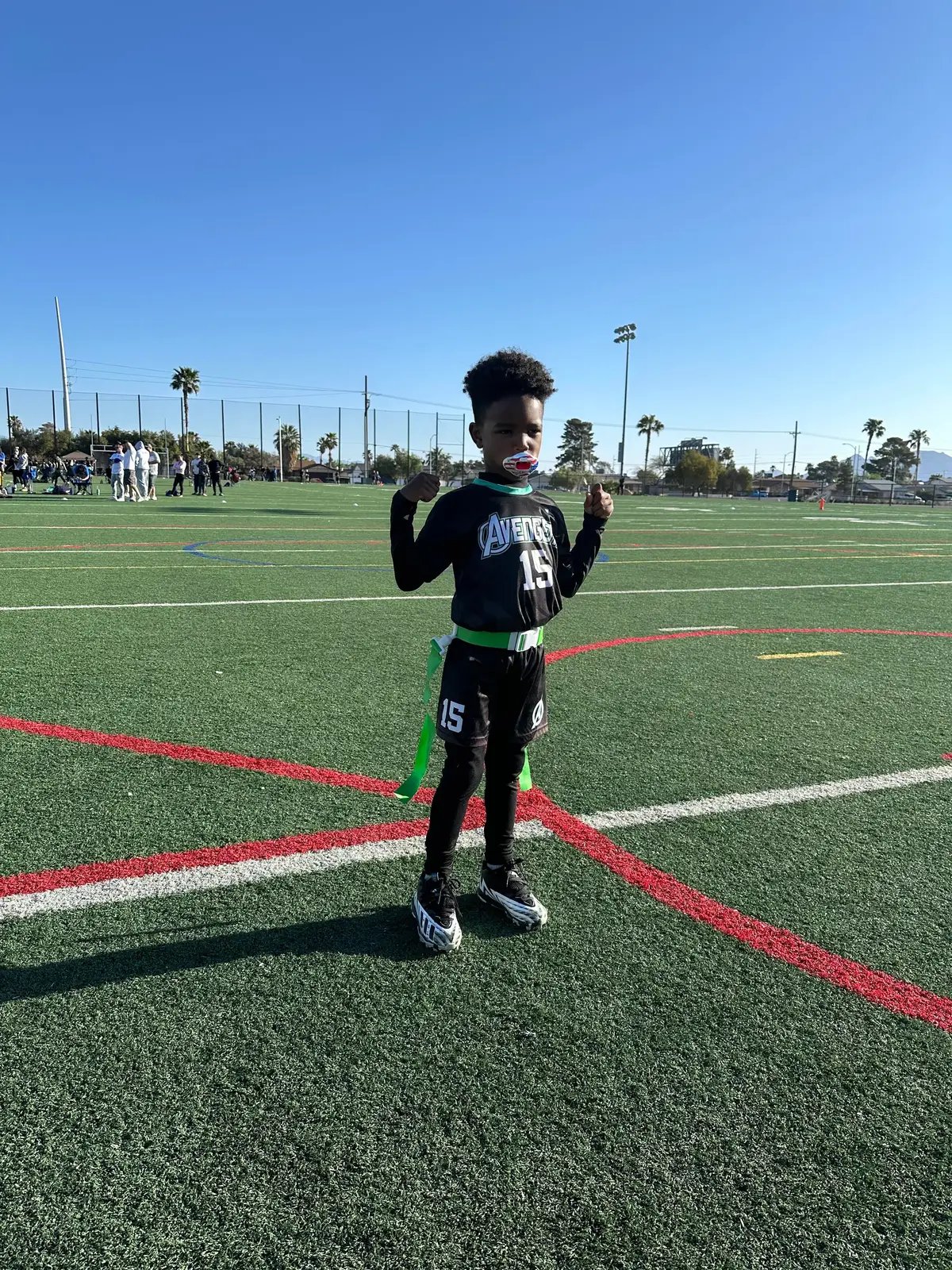 Flag football player in a black Avengers uniform on an outdoor field